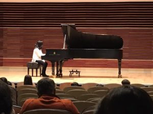 student at UT recital hall playing piano